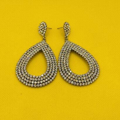 Elegant crystal teardrop earrings with multi-row design on yellow background Sparkling teardrop statement earring displayed on white holder with crystals Pair of crystal teardrop statement earrings laid flat on yellow background