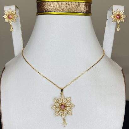 Elegant floral pendant necklace featuring a ruby-red centerpiece, encrusted with sparkling white stones and a delicate teardrop charm on a fine chain.