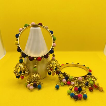 Golden bangles decorated with colorful pom-poms and delicate dangling charms, traditional ethnic jewelry for weddings, mehndi, and festive celebrations."