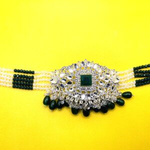 Traditional South Asian bridal jewelry set featuring large emerald green stone jhumka earrings and matching beaded choker or headpiece.